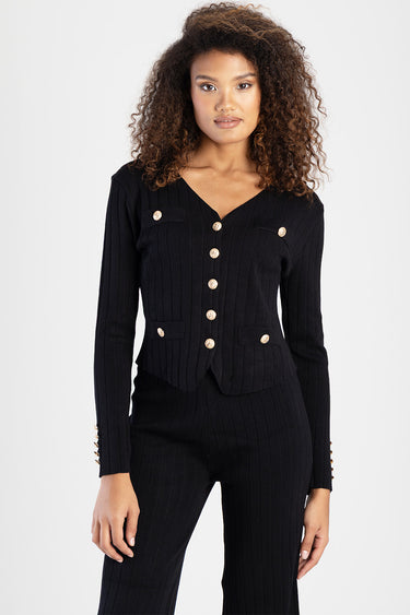 woman in black ribbed knit cardigan with gold buttons and matching knit pants, pocket flaps on the cardigan
