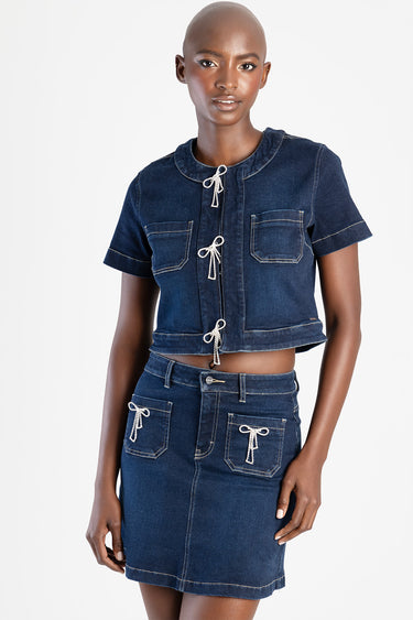 woman wearing a dark indigo denim cropped top with rope ties and a matching high waist denim skirt with front pockets