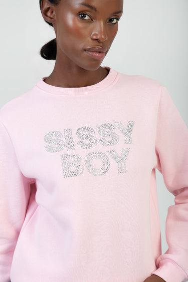 woman wearing a light pink crew neck sweatshirt with rhinestone letters spelling sissy boy across the chest