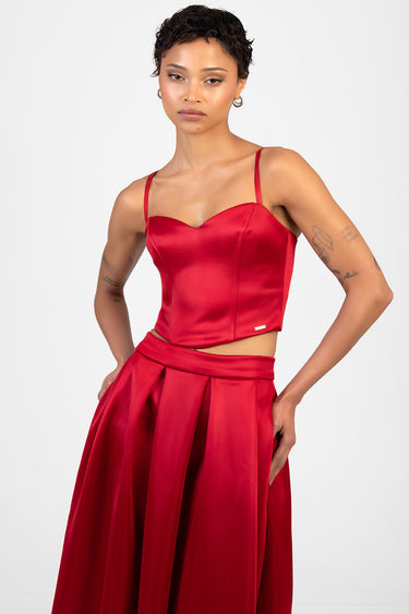 model wearing a red satin corset top with thin straps and a matching high waist red skirt
