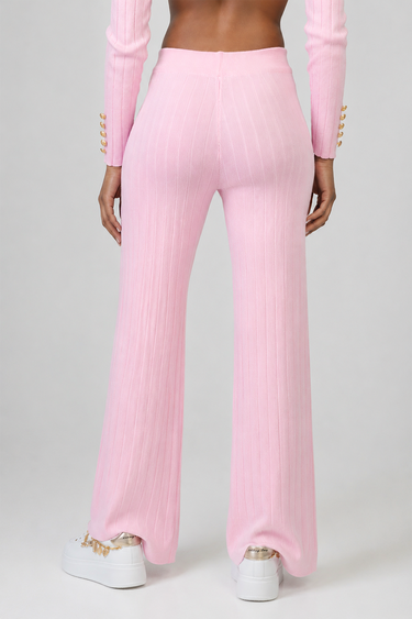 back view of pastel pink knit pants with vertical ribbing, high waist, and wide legs, paired with pink sleeves and white