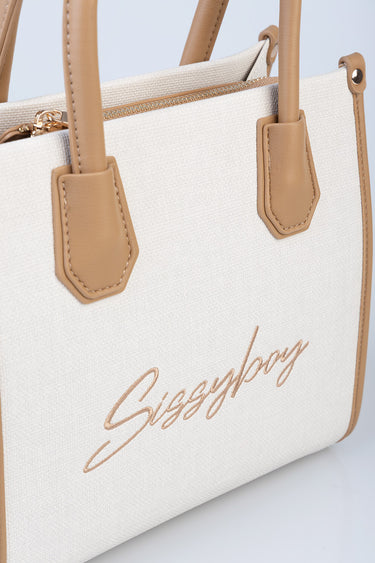 cream canvas bag with tan leather trim and handles, gold zipper, and script logo on front