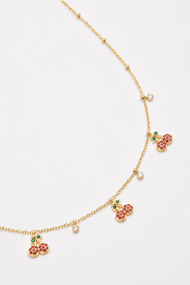 gold tone necklace with red cherry charms and green leaves along a delicate chain with clear crystal spacers