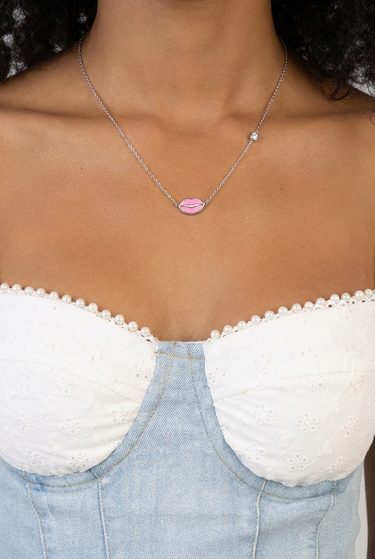 pink lips pendant on a silver chain worn over a denim strapless top with pearl trim