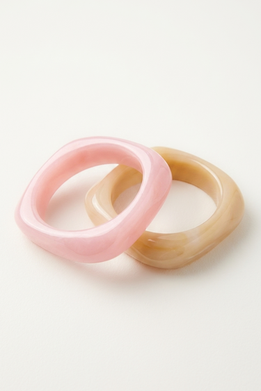 pink and beige resin bangles stacked together on a white surface