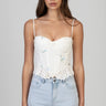 woman wearing a white corset top with floral embroidery and a scalloped lace hem, thin straps, paired with light wash jeans
