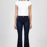 woman wearing dark indigo flare jeans with white sneakers and a white fitted t shirt