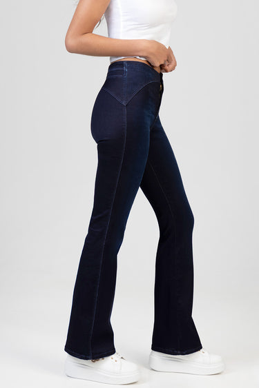 side view of woman wearing dark indigo bootcut jeans with white sneakers and a white crop top