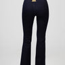 back view of navy blue flared jeans with a small metal tag at the waistband on a model wearing white sneakers