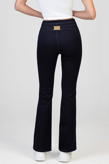 back view of navy blue flared jeans with a small metal tag at the waistband on a model wearing white sneakers