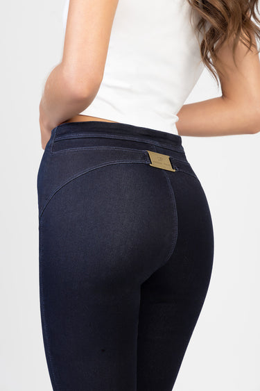 woman wearing dark indigo jeans by Blue Jean Traders, back view shows curved seat and a gold brand tag on the waistband