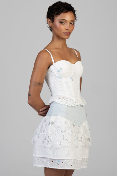 female model in white embroidered strap top and tiered eyelet lace skirt with light blue waist detail