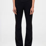 model wearing black knit denim pants with a crossover waistband and white sneakers