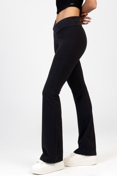 side view of a person wearing black knit denim pants with a wide waistband and flared legs, paired with white sneakers