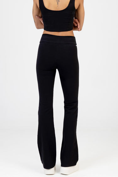 back view of a person wearing black knit denim pants with a wide waistband and flared legs, white sneakers