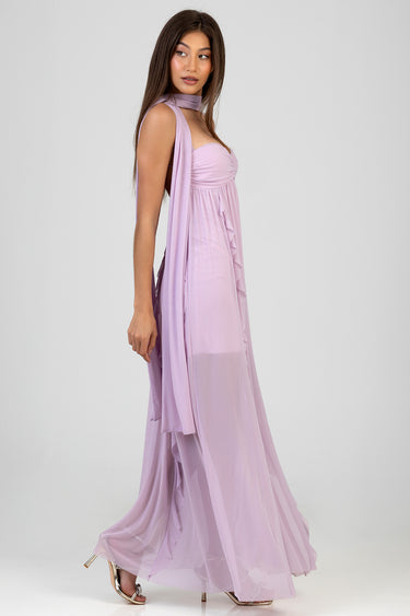 woman in a lavender maxi dress with flowing chiffon layers and a draped scarf over her shoulder, standing sideways in heels