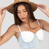 woman wearing a wide brim straw hat with pearl accents, white lace bustier and light blue denim corset top