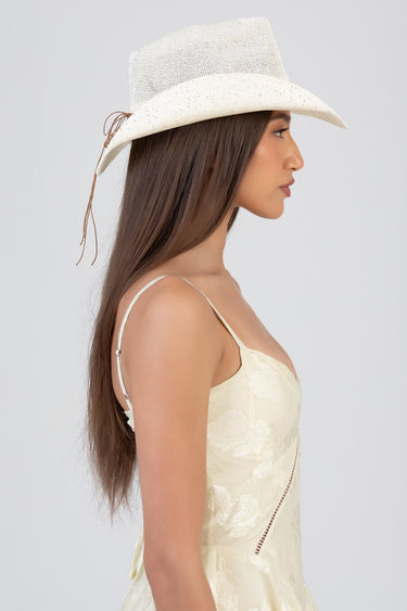 side view of a woman wearing a white sequined western hat with a tall crown and curved brim