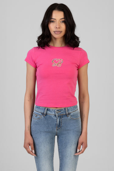 woman wearing bright pink short sleeve t shirt with a small sequin butterfly on the chest paired with faded blue denim jeans