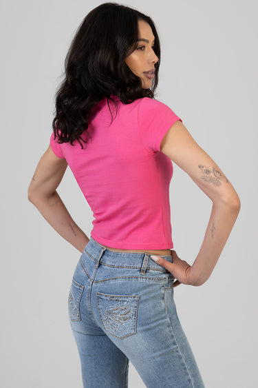 woman wearing bright pink cropped short sleeve t-shirt, side profile, paired with light blue jeans with embroidery on the