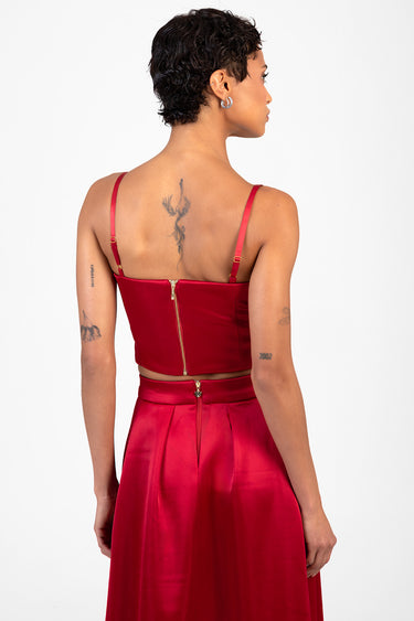 back view of woman wearing a red satin corset top with thin straps and matching high waist skirt; gold back zippers on both