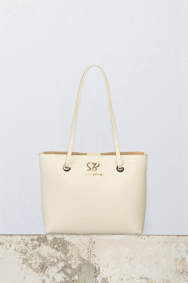 cream coloured tote bag with embossed floral pattern, gold hardware and two long straps
