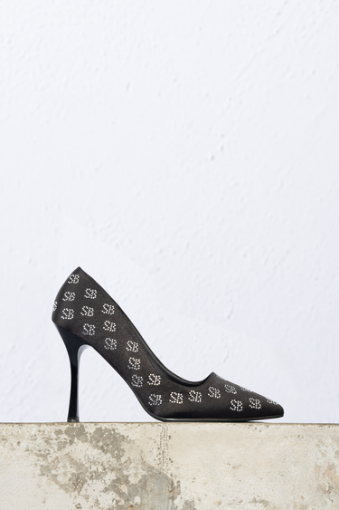 black stiletto heel with silver stud embellishments on a dark fabric