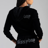 woman in black velour tracksuit with hood, rhinestone lettering on back of hoodie and on back of pants