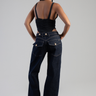 back view of a woman in dark blue wide leg jeans with gold buttons and pockets, black ruched tank top