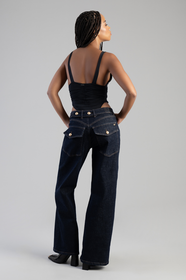 back view of a woman in dark blue wide leg jeans with gold buttons and pockets, black ruched tank top